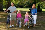 Happy Family Riding Bikes In A Park