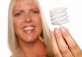 Attractive Blonde Woman Holds Energy Saving Light Bulb Isolated on a White Background with Narrow Depth of Field.
