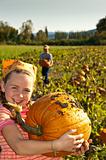 young girl with large pumpkin, in field