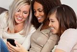 Three Female Friends Laughing and Looking at Cell Phone