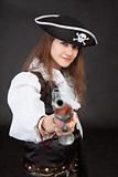 Young woman in suit of the pirate aims a pistol