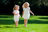 Two Pretty Young Girls Running Through A Sunlit Green Park