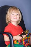 boy with long blond hair sitting in an office chair holding binoculrars