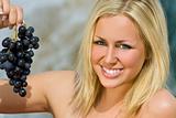 Beautiful Young Blond Woman Eating A Bunch of Grapes