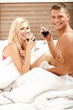 Couple sharing a drink in bedroom
