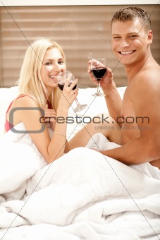 Couple sharing a drink in bedroom