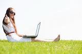 young feamle sit in the park and using a laptop