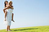 Woman giving young girl piggyback ride