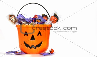 Jack-o-Lantern bucket filled with candies on white 