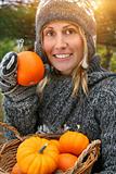 Pretty young woman holding basket of pumpkins