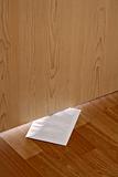 white envelope with message slipped under wooden door