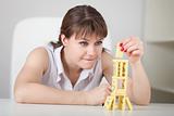 Beautiful young woman builds tower of dominoes