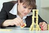 Young woman builds tower of dominoes bones on table