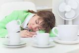 Woman has got tired and sleeps on table among coffee cups