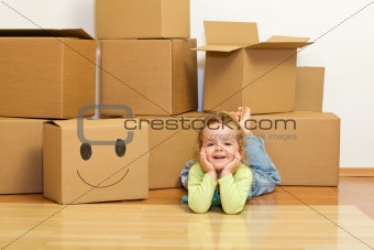 Little girl laying on the floor with lots of cardboard boxes