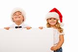Happy kids with santa hats and white cardboard