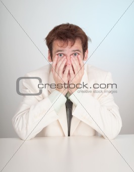 Young sorrowful people in white suit sits at table