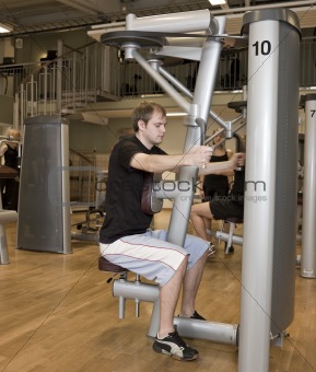 Young man using an exercise machine 