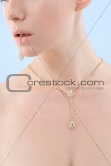 Young woman holding golden bracelet in her mouth