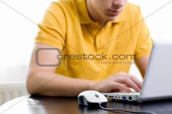 Young man in yellow shirt is sitting in front of his notebook