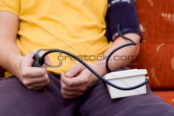 Man in yellow shirt is checking his blood pressure