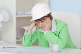 Woman - engineer in protective helmet sits at table on workplace