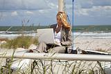 Beautiful Young Woman Using Laptop On Boat At The Beach