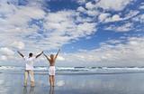Man and Woman Couple Celebrating Arms Raised On A Beach