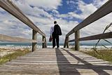 Businessman Standing Barefoot Looking Across A Beach To The Sea
