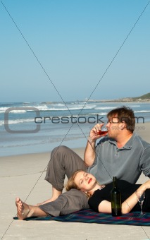 Young couple enjoying the wine on the beach