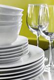 Stack of commercial white dishes and crystal wine glasses