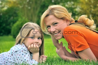 Young mother and daughter laying on the grass