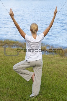Beautiful Young Woman Practicing Yoga By A Tranquil Blue Lake