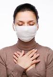 Young woman in medical mask keeping hands on chest