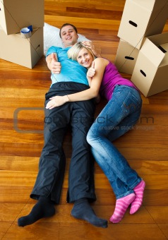 Young couple sleeping on the floor with boxes around. Moving house