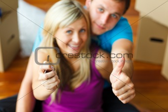 Woman and man holding a key with thumbs up. Buying new house
