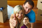 Couple holding a key with thumbs up. Buying new house