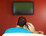 Couple sitting on couch watching a television at home