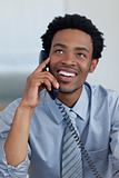 Attractive smiling Afro-American businessman on phone in office