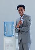 Businessman drinking from a water cooler in office
