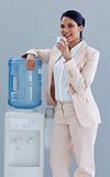 Businesswoman drinking from a water cooler