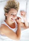 Beautiful woman lying in bed smiling at the camera