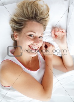 Beautiful woman lying in bed smiling at the camera