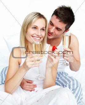 Young lovers eating strawberries and drinking champagne