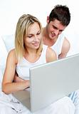 Couple reading using a laptop in bed