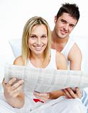 Young couple with a newspaper in bed