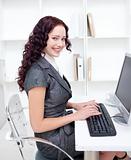 Smiling businesswoman working in office with a computer