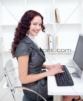 Smiling businesswoman working in office with a computer
