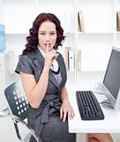 Young businesswoman shushing with her finger in office
