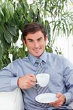 Businessman drinking a cup of coffee on sofa